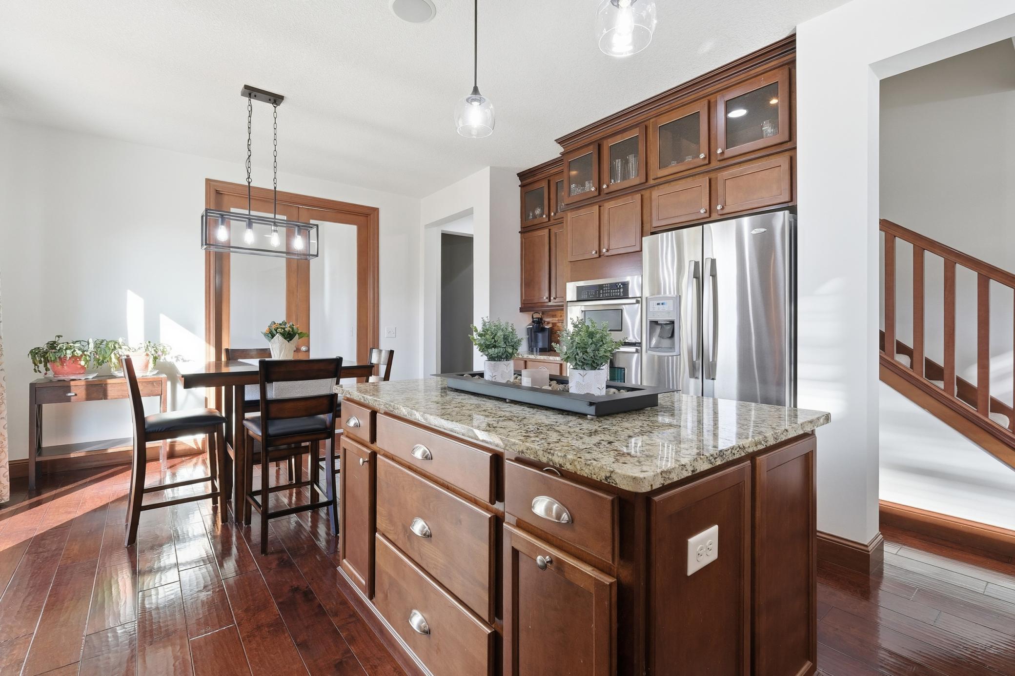 The spacious gourmet kitchen features both a center island as well as a bar area for maximum entertaining and prep space. The upper glassed cabinets and backsplash along with the appliances are all upgrades.
