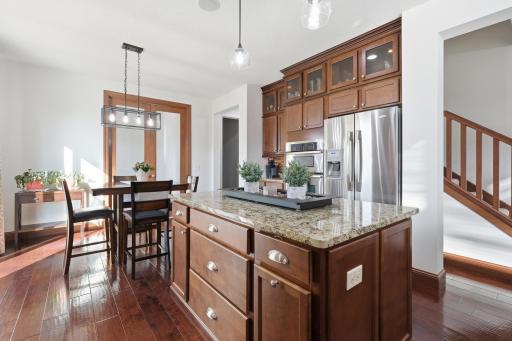 The spacious gourmet kitchen features both a center island as well as a bar area for maximum entertaining and prep space. The upper glassed cabinets and backsplash along with the appliances are all upgrades.