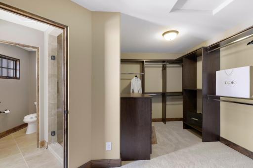 Retire to the luxurious primary ensuite with panoramic lake views, vaulted ceilings, natural stone-topped vanity with dual sinks, a soaker tub, a walk-in shower with two shower heads, and a huge walk-in closet.