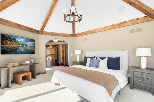 Retire to the luxurious primary ensuite with panoramic lake views, vaulted ceilings, natural stone-topped vanity with dual sinks, a soaker tub, a walk-in shower with two shower heads, and a huge walk-in closet.