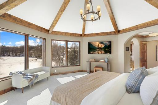 Retire to the luxurious primary ensuite with panoramic lake views, vaulted ceilings, natural stone-topped vanity with dual sinks, a soaker tub, a walk-in shower with two shower heads, and a huge walk-in closet.