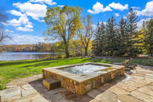 A generously sized, inground hot tub on the lower patio boasts decorative lighting and water features providing the perfect place to unwind after a long day on the lake.
