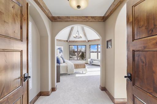 Retire to the luxurious primary ensuite with panoramic lake views, vaulted ceilings, natural stone-topped vanity with dual sinks, a soaker tub, a walk-in shower with two shower heads, and a huge walk-in closet.