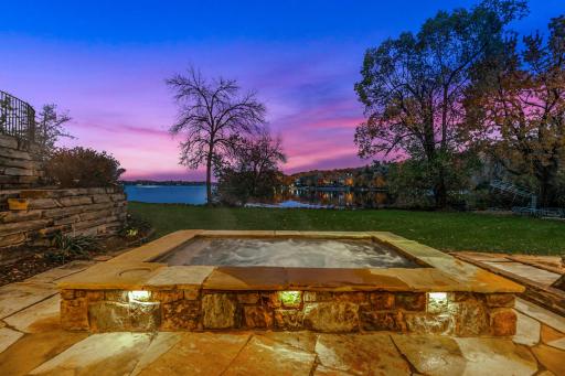 A generously sized, inground hot tub on the lower patio boasts decorative lighting and water features providing the perfect place to unwind after a long day on the lake.