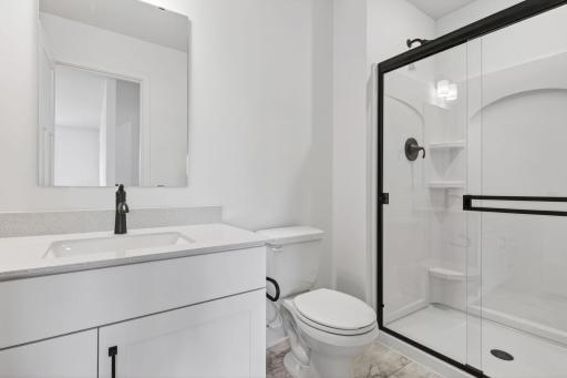 A private bathroom offers a shower with built-in shelves and a quartz-topped vanity with a MoenÂ® chrome-finish faucet