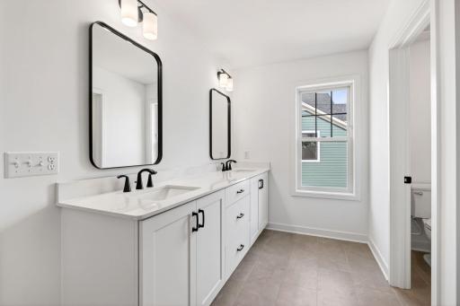 Double sinks, MoenÂ® brushed-nickel faucets and quartz countertops gleam in the ownerâs suite bathroom
