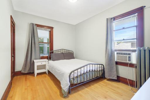 One of two bedrooms in the upper unit featuring hardwood floors, neutral tones, and plenty of natural light.