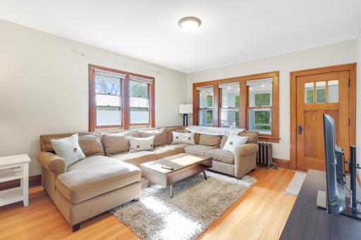 The living room features neutral tones and abundant natural light from multiple windows, creating an open and bright space.