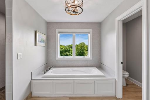 Primary bath features large soaking tub, tiled walk-in shower, dual vanities, and separate water closet