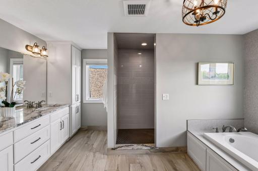 Primary bath features large soaking tub, tiled walk-in shower, dual vanities, and separate water closet