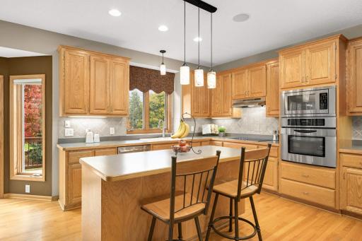 Kitchen provides a large center island, ample cabinetry, and tile backsplash.