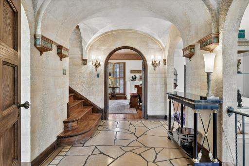 Large entryway with limestone tiled floors, vaulted arches, and hand painted plaster walls.