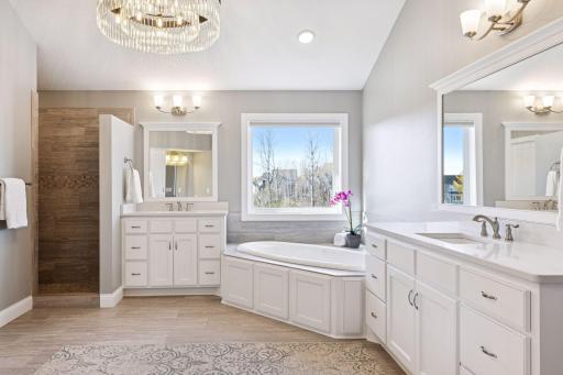 Spa-inspired luxury with dual vanities, plus a makeup vanity, walk-in shower with dual shower heads, private water closet, linen closet, and jetted tub overlooks nature views.
