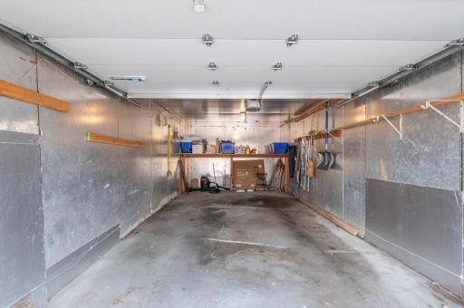The inside of the garage has insulation placed on the walls, a newer garage opener, and door.