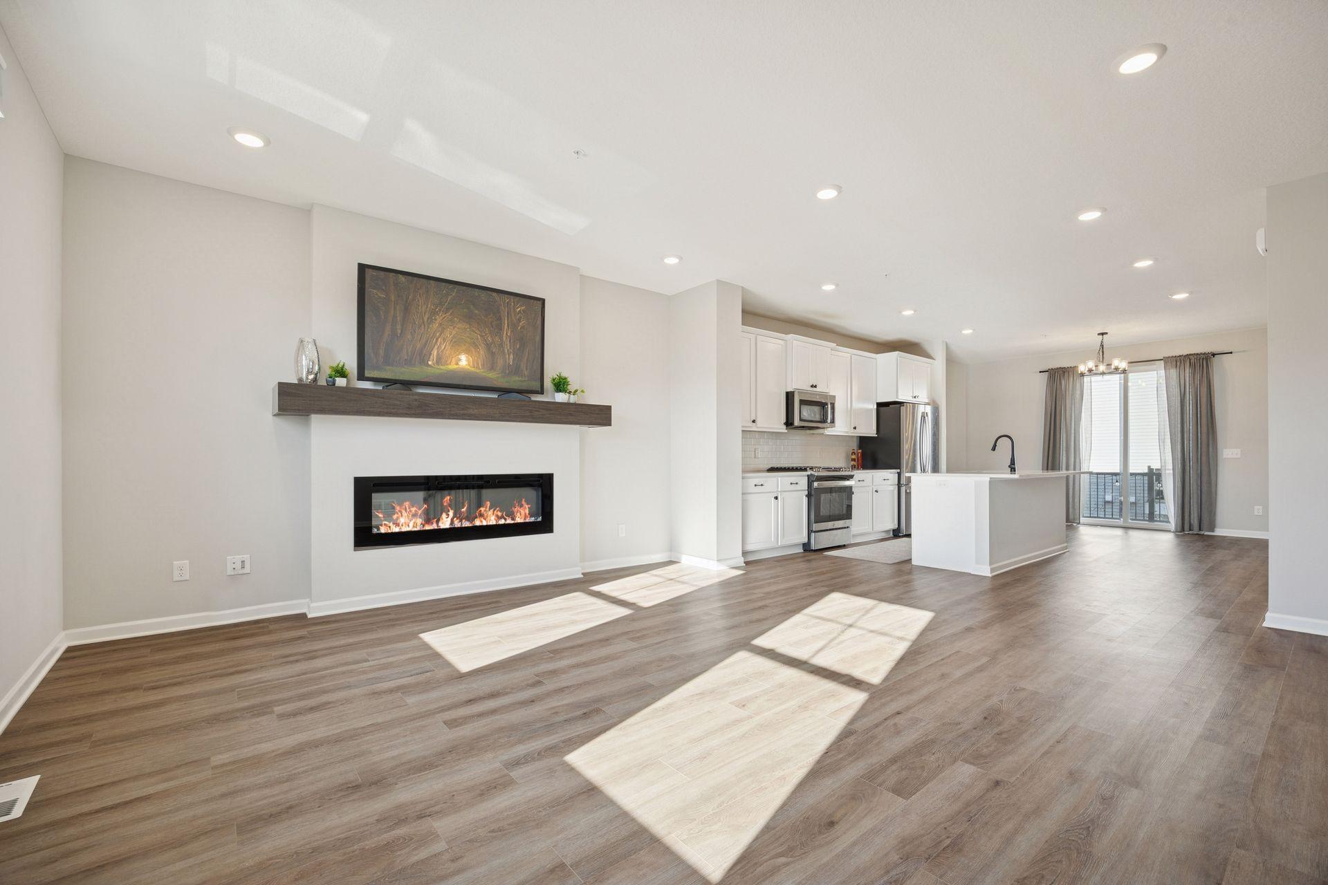 Main level bright and open living area filled with natural light. Features a modern electric fireplace, large windows and plenty of space to relax or entertain