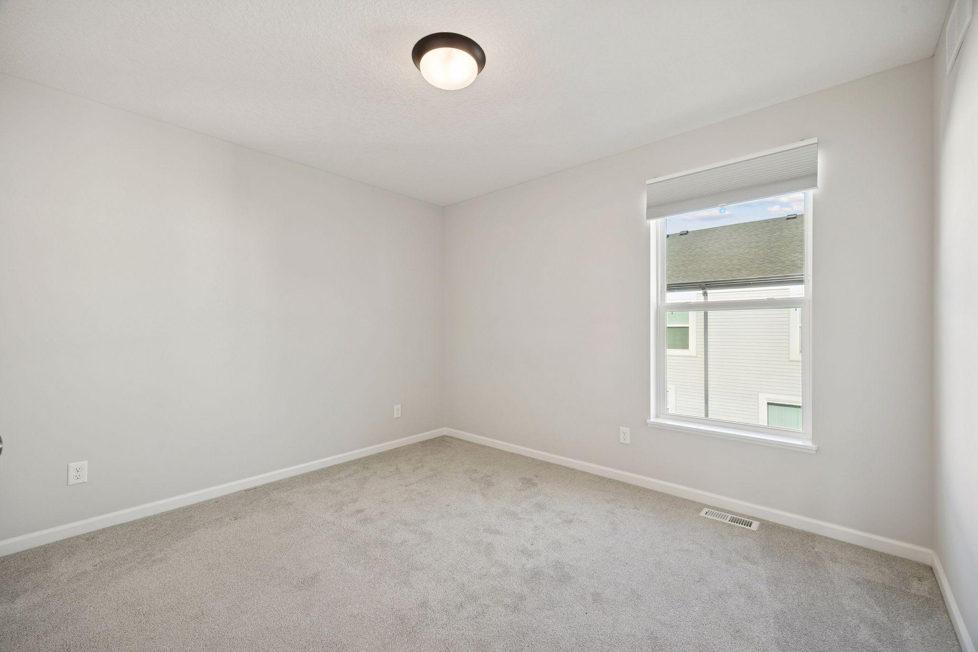 Upper level bright third bedroom with neutral walls, soft carpet and double closet doors for extra storage.