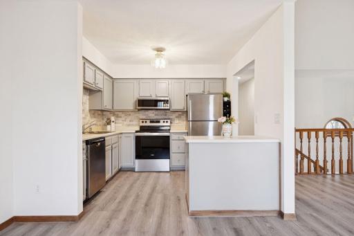 Bright kitchen with updated gray cabinetry, stainless steel appliances and modern lighting.