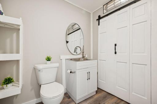 Updated half bath with a modern vanity, round mirror and charming barn doors with laundry tucked right behind.