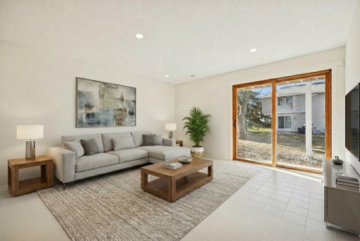 Bright lower-level family room with recessed lighting, neutral tile flooring and large patio doors bringing in natural light. Virtually staged.