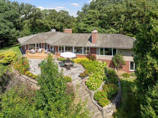 Incredible landscaping, thoughtfully designed to enhance both privacy and beauty, features a flagstone patio and steps leading to the lake, surrounded by lush perennial shrubs, bushes, and colorful annual flower beds.
