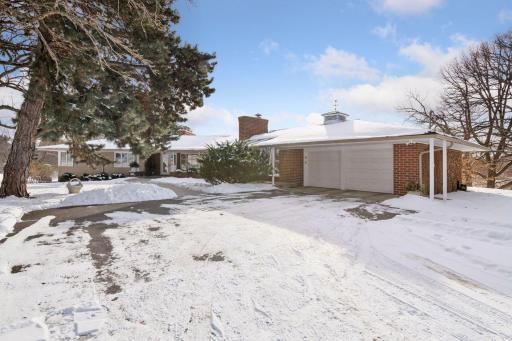 Winter view of driveway and garage. There is a circular driveway adjacent to the garage