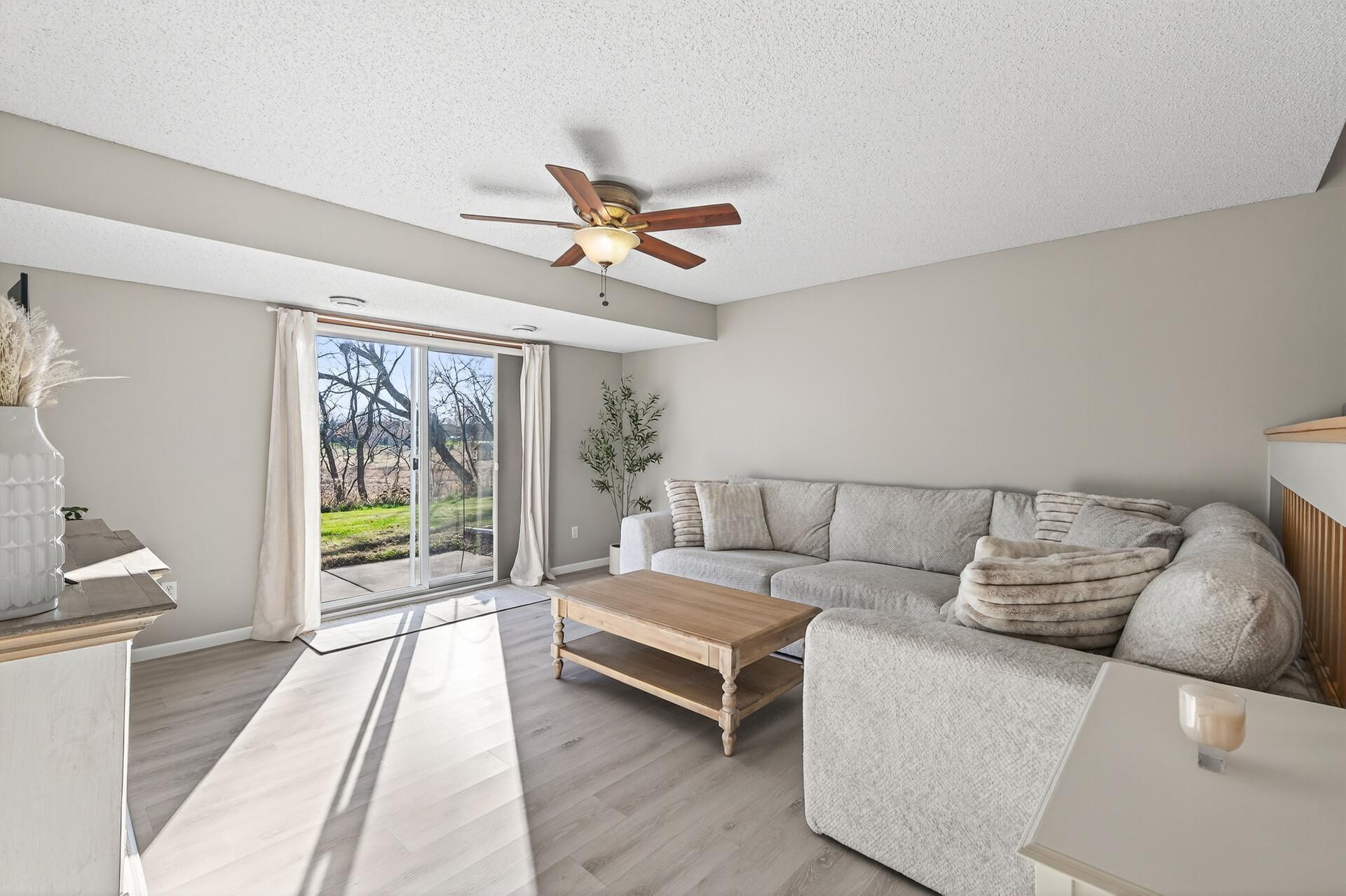 Comfortable lower-level living room with updated flooring, large patio door, natural light, and walkout access to the backyard/patio area.