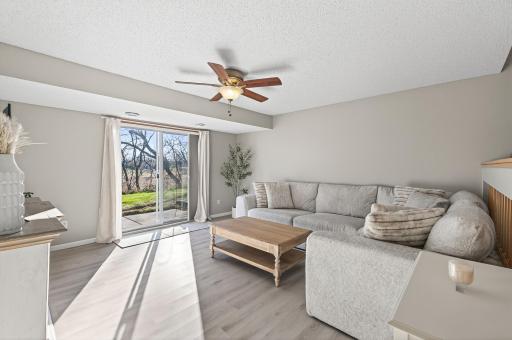 Comfortable lower-level living room with updated flooring, large patio door, natural light, and walkout access to the backyard/patio area.