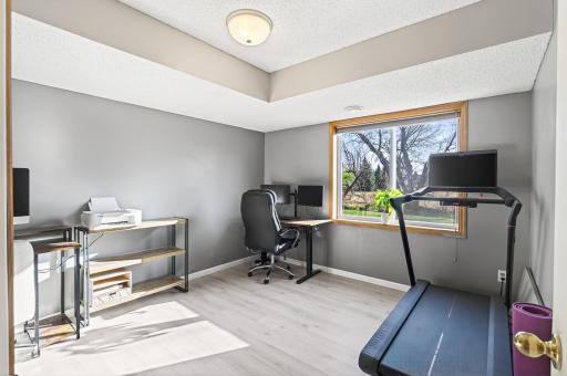 Flexible bedroom or office space with a large window, updated flooring, and room for work, fitness, or guest use.