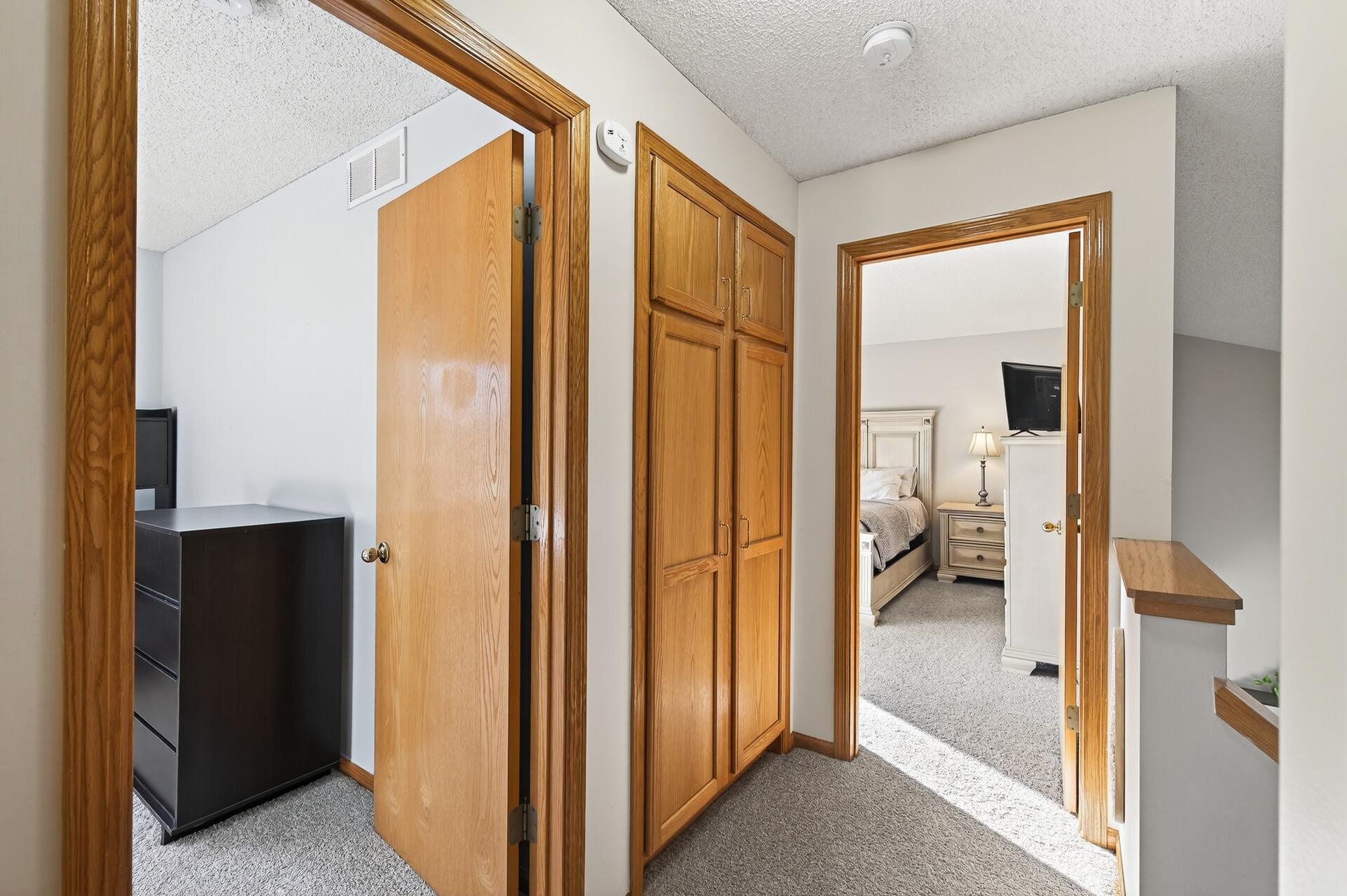 Upper-level hallway with bedroom access and built-in linen/storage cabinetry.