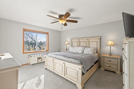 Spacious bedroom with neutral paint, ceiling fan, large window, and comfortable natural light.