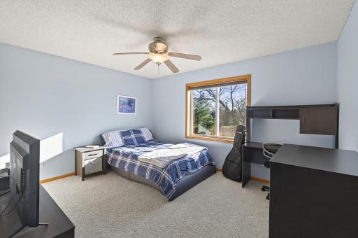 Comfortable secondary bedroom with large window, ceiling fan, and space for a desk or bedroom furniture.