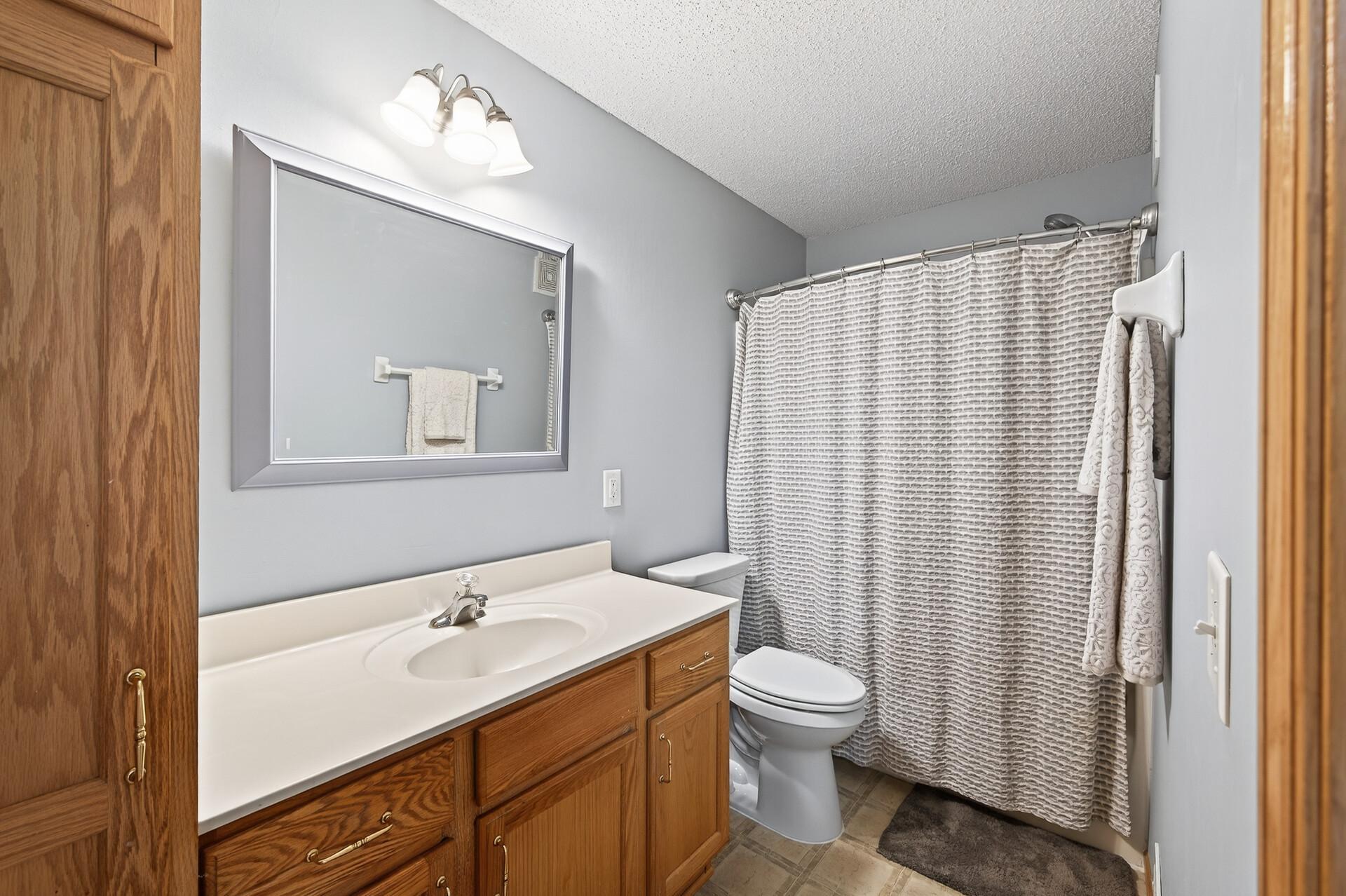 Second full bath with tub/shower combo, updated lighting, extended vanity, and neutral finishes.