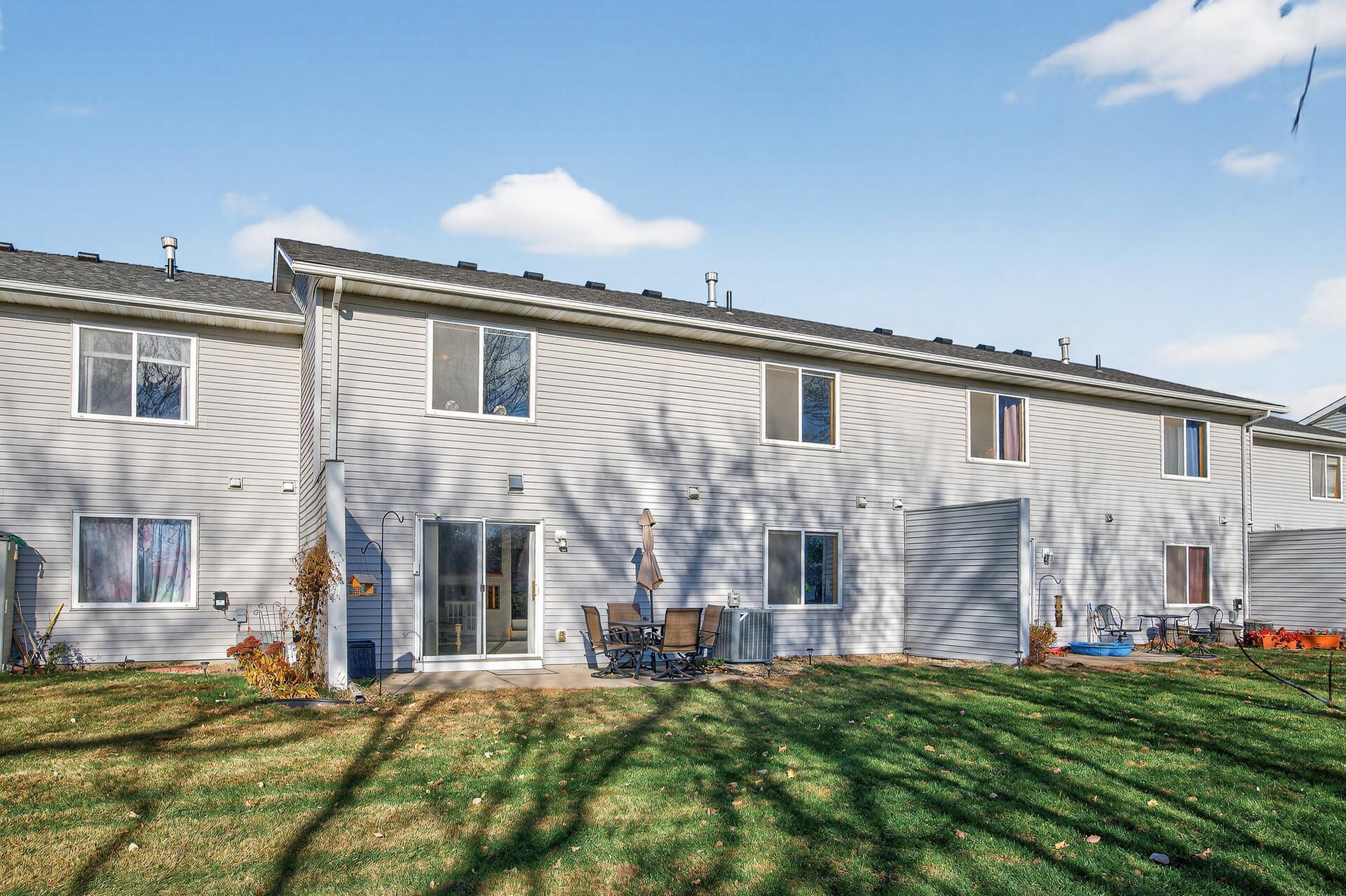 Rear exterior view with walkout patio, shared green space, and mature tree views.