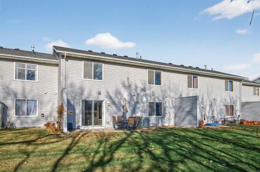 Rear exterior view with walkout patio, shared green space, and mature tree views.