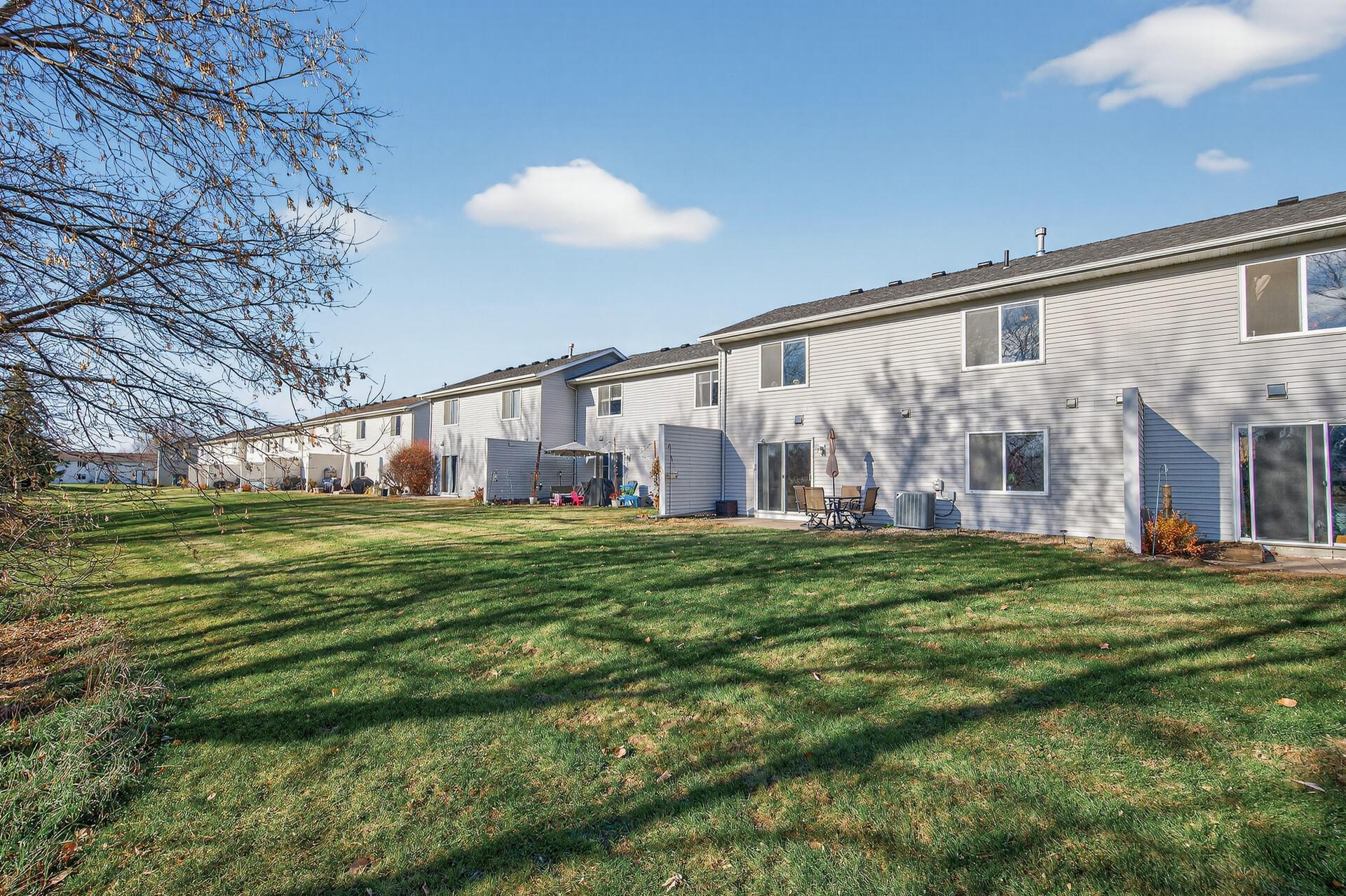Spacious common green area behind the home with mature trees and an open, relaxed setting.