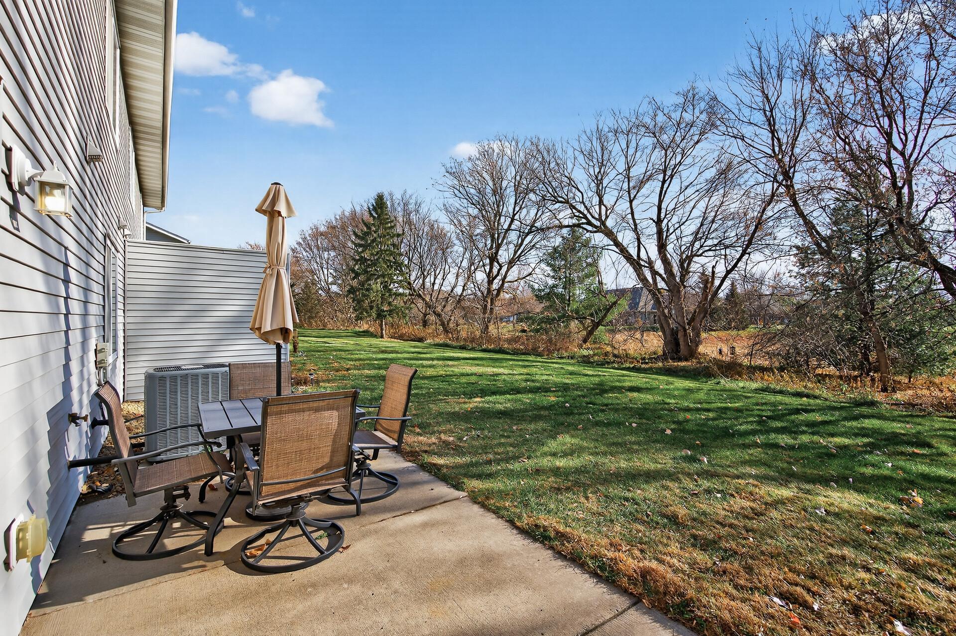 Outdoor patio offers room for dining or relaxing while overlooking the grassy common area and mature trees.