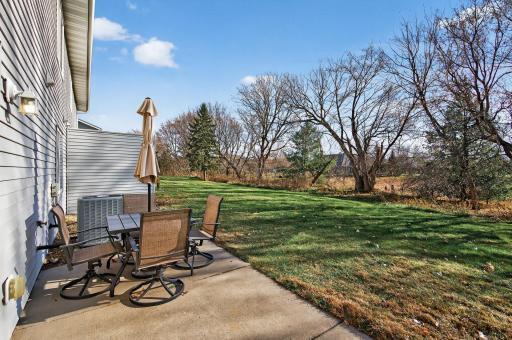 Outdoor patio offers room for dining or relaxing while overlooking the grassy common area and mature trees.