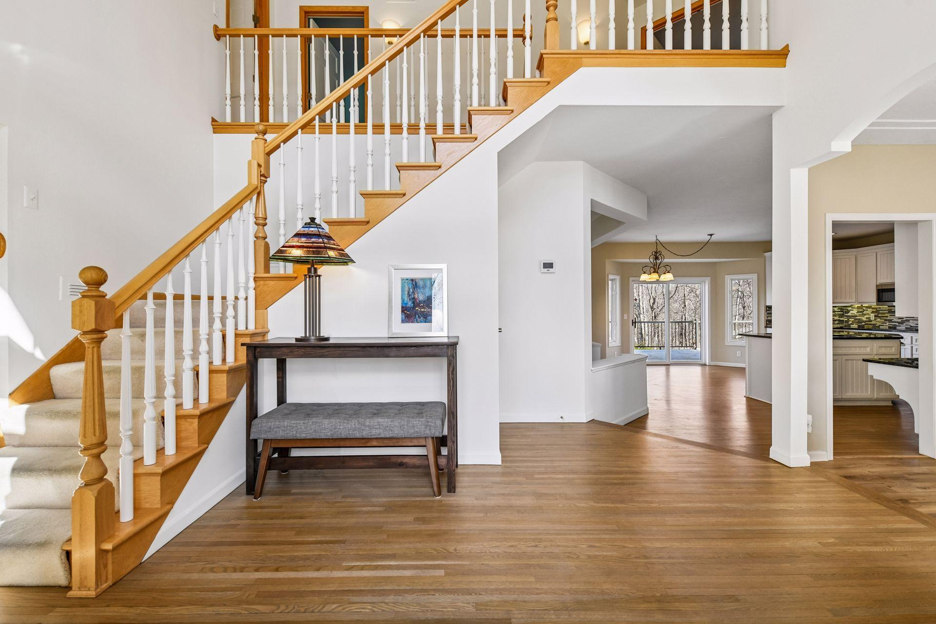 The inviting two-story entryway showcases an open-concept flow to the formal dining room, informal dining with deck access, and a peek into the updated kitchen with white cabinetry!