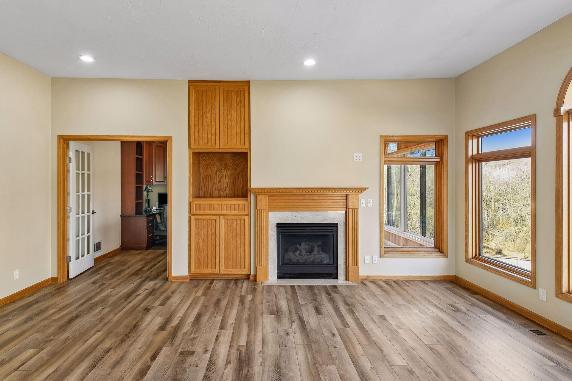 Another view of the family room featuring a wood-surround fireplace and custom built-ins. Large windows pull in abundant light from the porch and deck!