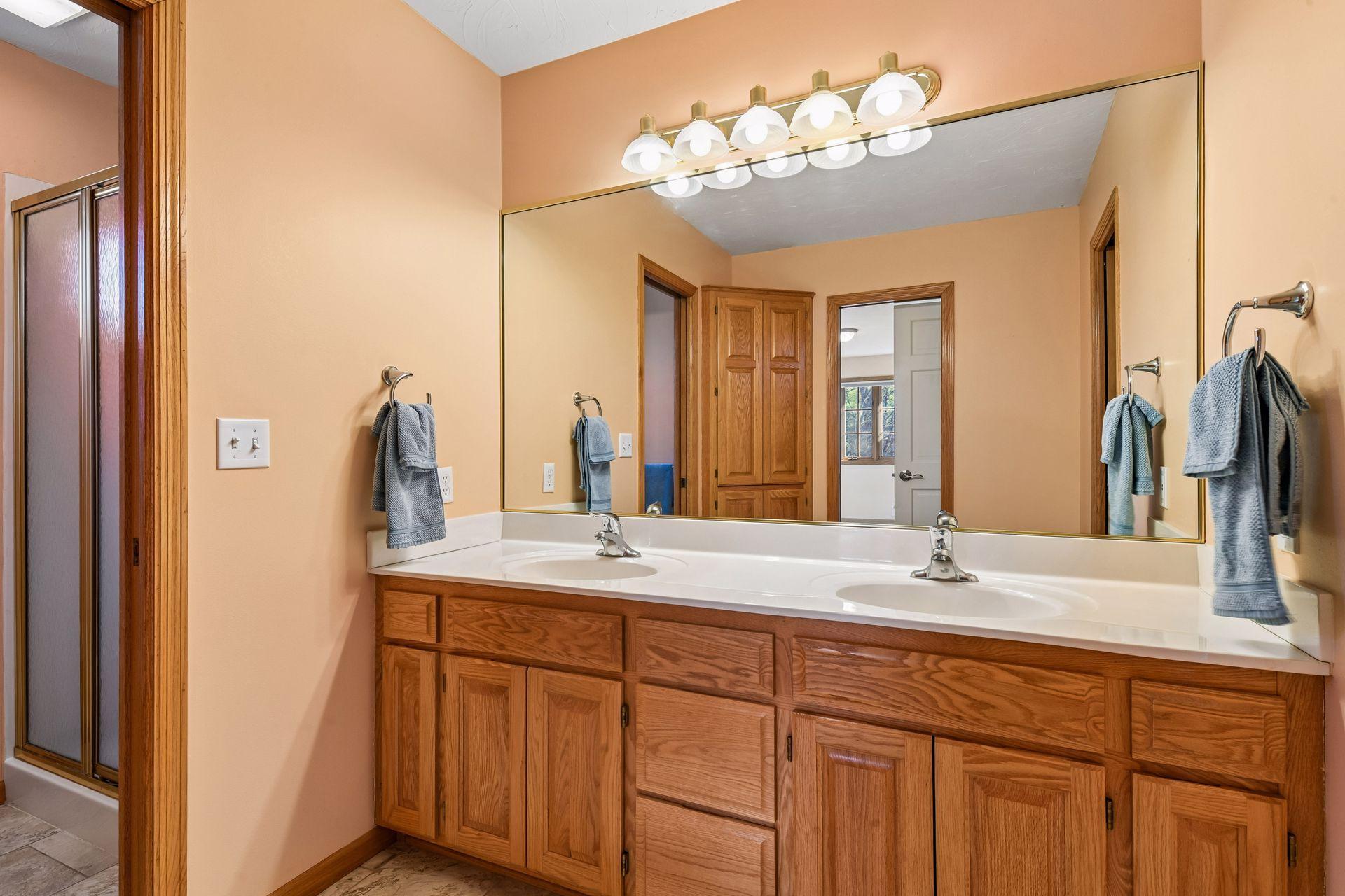 Efficient upstairs Jack and Jill bathroom featuring a dual vanity with ample storage. A private separate room with a sliding shower door and toilet ensures privacy and functionality for everyone!