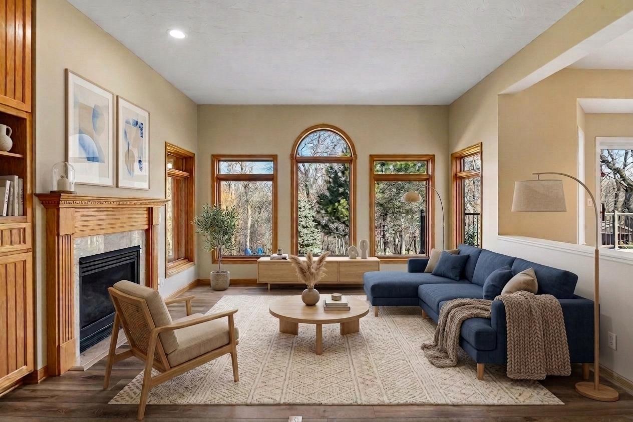 The inviting living area anchored by a warm wood-surround fireplace and stunning arched windows that frame tranquil wooded views. Rich wood built-ins offer custom style! *Virtually staged to show design options.