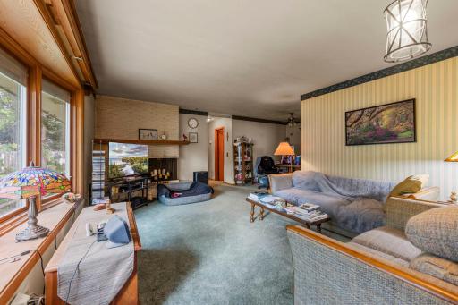 The main-level living room is generously sized and features a charming bay window and a cozy wood-burning stove. *Hardwood floors under the carpeting.