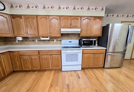 Oak kitchen cabinets & oak hardwood flooring are featured in the spacious kitchen.