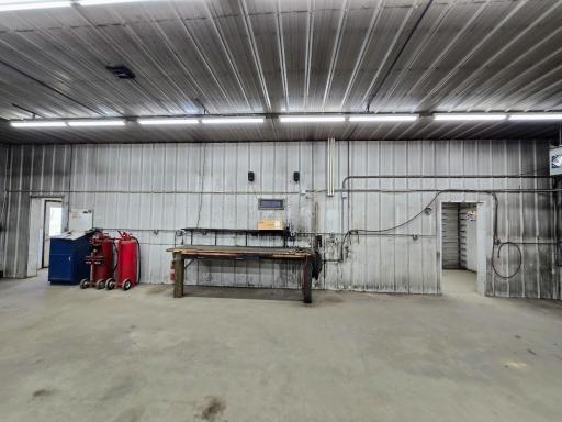 West wall with mulitiple outlets, work bench & south door to office & north door to storage room