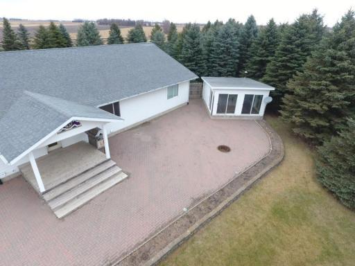Bird's eye view of the covered front porch, paver patio with firepit, & greenhouse.
