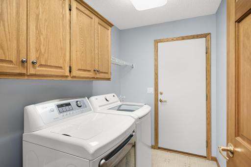 Main floor laundry room with utility sink and cabinet storage. This is 1 of 2 doors that leads to the garage. You can also access the garage from the door in the foyer.