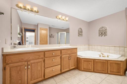 Primary bathroom offering dual sinks, separate soaking tub and shower. Tile floors and tile surround.
