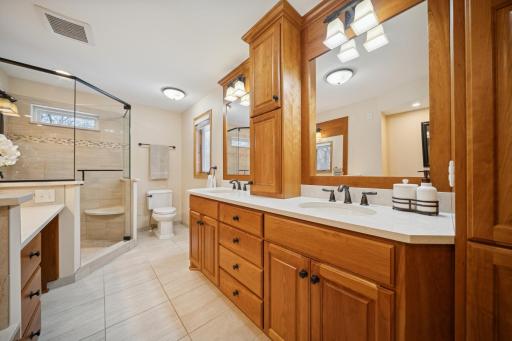 Dual vanity, toilet, and glass surround shower.