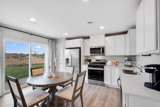 Modern kitchen with white cabinets, quartz countertops and stainless appliances. Photo is of model home. Colors and options may vary. Ask Sales Agent for details.