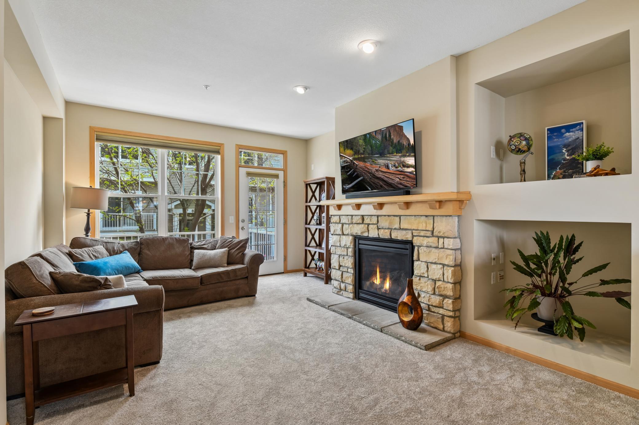 Sunny, open living room with 9 ft ceilings, cozy stone fireplace, and new carpet, pad, and paint 2026!
